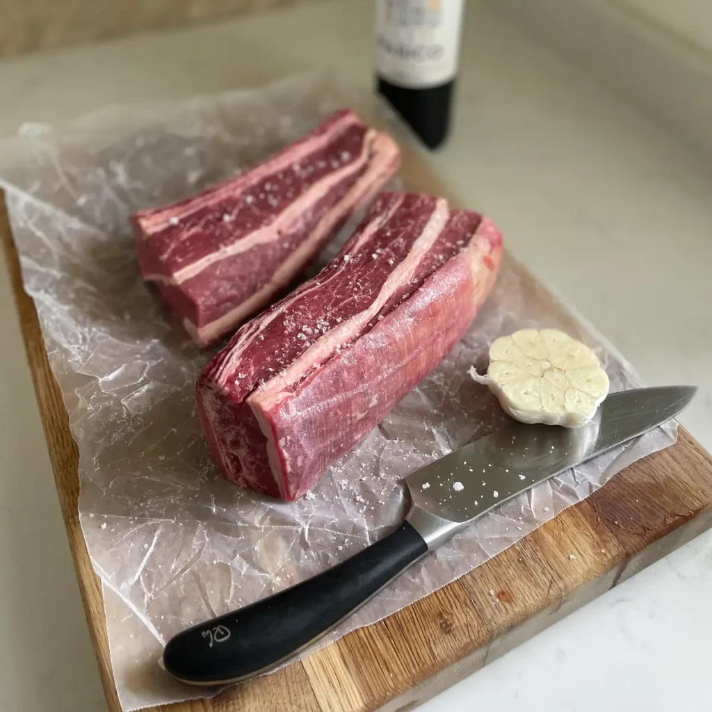 Two beef short ribs on a chopping board